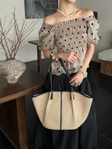 Raffia geweven shopper tas detail met zwarte lederen handvatten en ruim ontworpen stijl.