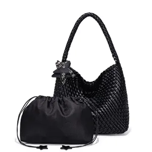 Close-up of black woven shoulder handbag featuring braided strap, star charm and inner pouch.