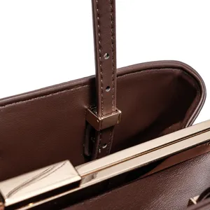 Nahaufnahme der braunen Handtasche innen, Metallverschluss und verstellbarer Riemen.
