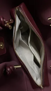 Detailed view of the wine red handbag interior with zippered pocket and lining.