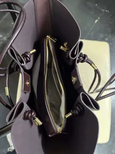 Top-down interior detail of dark purple leather tote bag with middle zipper pouch and gold hardware
