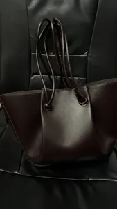 Dark brown pleated leather tote bag detail, featuring long slim straps and spacious capacity.