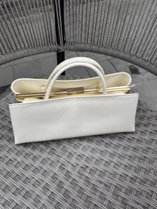 Elegante weiße Handtasche aus Leder mit strukturiertem Retro-Design und goldenen Beschlägen.