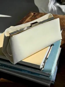 Detailansicht der eleganten weißen Leder-Clutch Handtasche mit metallischem Rahmenverschluss.