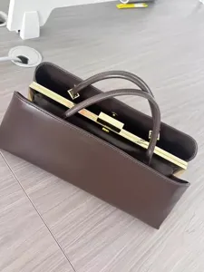 Braune Vintage-Rahmenhandtasche Detail, elegantes goldenes Metallschloss und zwei Griffe.