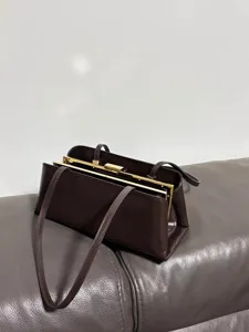 Detailansicht der retro dunkelbraunen Schultertasche mit edlem Goldmetallrahmen und schmalem Gurt.