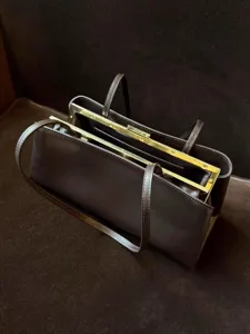 Detaillierte Nahaufnahme der dunklen braunen Vintage Ledertasche mit goldenem Metallrahmen.