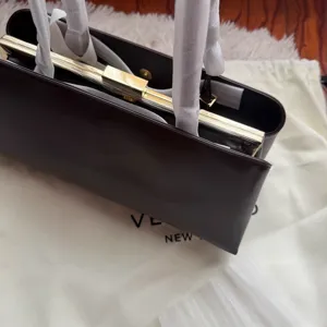 Detailaufnahme der eleganten dunkelbraunen Leder-Rahmentasche mit goldener Hardware und Griffen.