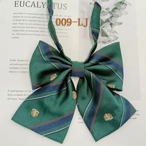 Detail shot of green plaid JK uniform bow tie with navy stripes and gold crest embroidery.