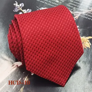 Detailed close-up view of a classic red jacquard patterned men tie on textured background.