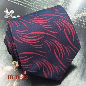 Navy blue men tie detail closeup featuring elegant red leaf jacquard pattern fabric texture.