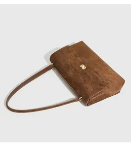 Detail view of a retro brown suede shoulder bag with gold-tone twist lock and sleek strap.
