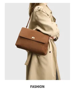 Detailed shot of a brown retro suede shoulder bag worn by a model in a beige trench coat.