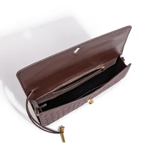 Detailed view of dark brown woven leather shoulder bag interior, showcasing craftsmanship and hardware.