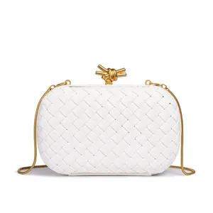 Nahaufnahme der weißen geflochtenen Clutch mit goldenem Knotenverschluss und feiner Kette.
