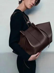 Gedetailleerd overzicht van de donkerbruine litchi lederen tote tas, elegant vleugelontwerp.