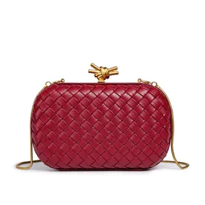 Nahaufnahme der roten geflochtenen Leder-Clutch mit goldener Metall-Knotenschließe.
