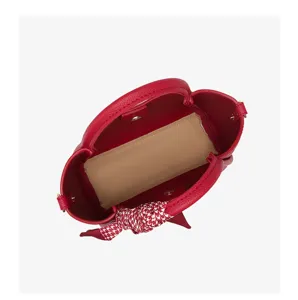 Vista superior detallada de un elegante bolso tipo cubo de cuero rojo con bufanda.