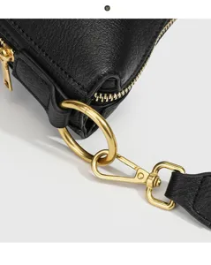 Nahaufnahme der schwarzen Ledertasche mit exakten goldenen Metallbeschlägen und Reißverschluss.