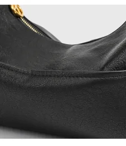 Schwarze Leder-Hobo-Umhängetasche Detail zeigt feine Textur und hochwertige Metallbeschläge.