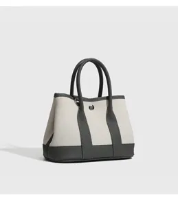 Dettaglio della borsa in tela con cuciture a contrasto, manici resistenti e bottone automatico.