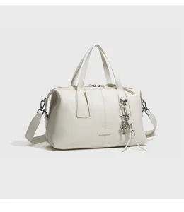 Bolso Boston de cuero blanco con elegante colgante de metal y bolso cruzado para mujer.