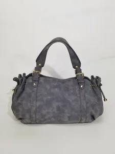 Detail view of grey suede handbag with buckle straps and gold-tone hardware details.