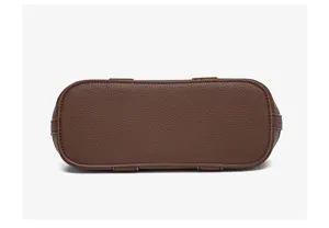 Brown leather handbag bottom detail shot showing neat stitching and structured oval shape.