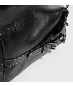 Vista detallada del bolso boston de cuero negro genuino con hebilla de metal y costuras blancas.