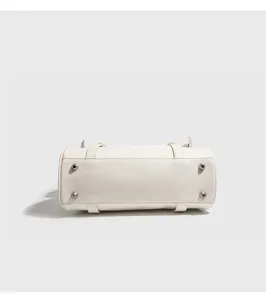 Detailed bottom view of a stylish white compact handbag featuring protective metal feet.