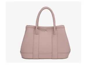 Pink leather tote bag detail showing fine texture, dual handles, and central snap closure.