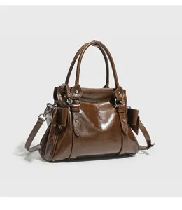Detail view of the retro brown leather handbag showing glossy texture, side bow and metal hardware.