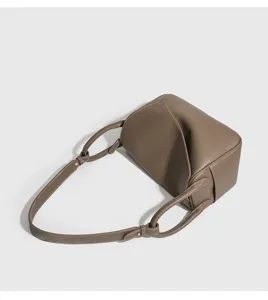Dettaglio borsa a tracolla minimalista in pelle taupe, patta elegante con spallacci annodati.