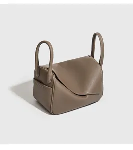 Dettaglio della borsa a tracolla in pelle tortora con patta elegante e manici laterali.