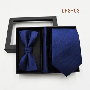 Primer plano detallado del conjunto de corbata, pajarita y pañuelo azul en caja de regalo.