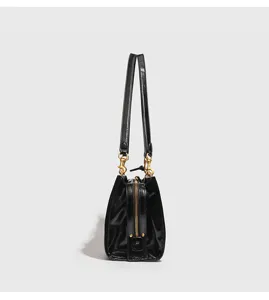 Vista lateral detallada del bolso de hombro para mujer de charol negro con herrajes dorados.