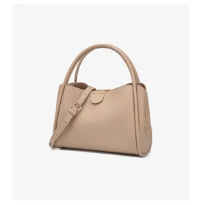 Bolso de mano de cuero beige con asa superior, correa ajustable y cierre central elegante.