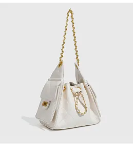 Detailed view of white quilted bucket shoulder bag with gold chain straps and drawstrings.