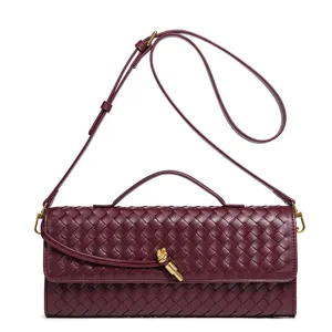 Elegant burgundy woven leather crossbody bag with top handle and chic metal knot closure detail.