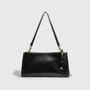 Elegante bolso de hombro de charol negro bolso bajo el brazo con herrajes dorados.