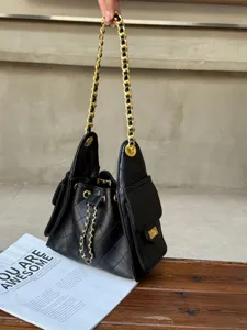 Detailed shot of black quilted shoulder bag with gold chain strap, elegant handbag close up.