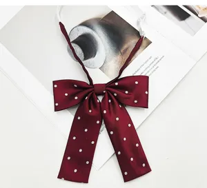 Close-up detail of a dark red JK bow tie with white polka dots, featuring a long stem design.