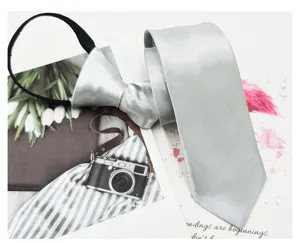 Corbata delgada plateada con cremallera primer plano, textura satinada lisa, accesorio formal.
