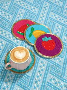 Detalle de posavasos de cuentas hecho a mano, mantelito con fruta creativa para taza y decor.