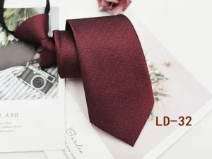 Burgundy textured zipper tie close-up, premium fabric detail shot showing fine shimmer texture.