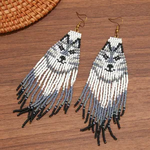 Handmade beaded fringe earrings featuring bohemian wolf animal pattern with long dangling seed beads design.