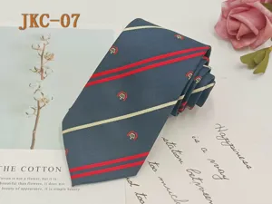 Detailed view of the navy blue JK uniform tie featuring red stripes and delicate crown embroidery.