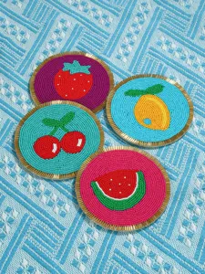 Detalle de posavasos de cuentas de frutas hechos a mano, manteles coloridos fresa limón.