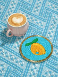 Vista de detalle en primer plano del posavasos de frutas con cuentas hecho a mano y borde dorado.