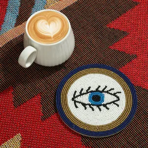 Gros plan sous-verre perles de rocaille fait main, détail motif œil turc bleu pour déco table.